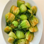 Baby bok choy stir fried with minced garlic and ginger in a white bowl