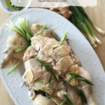 Bok Cheet Gai Slow Cooker Chinese White Cut Chicken on a white platter with some ginger, green onions, and sauce