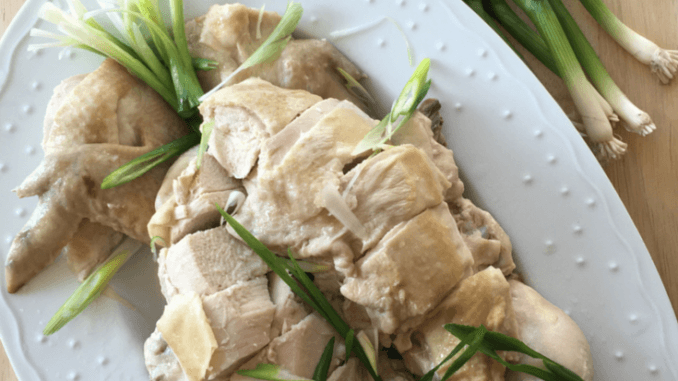 Bok Cheet Gai Slow Cooker Chinese White Cut Chicken on a white platter with some ginger, green onions, and sauce