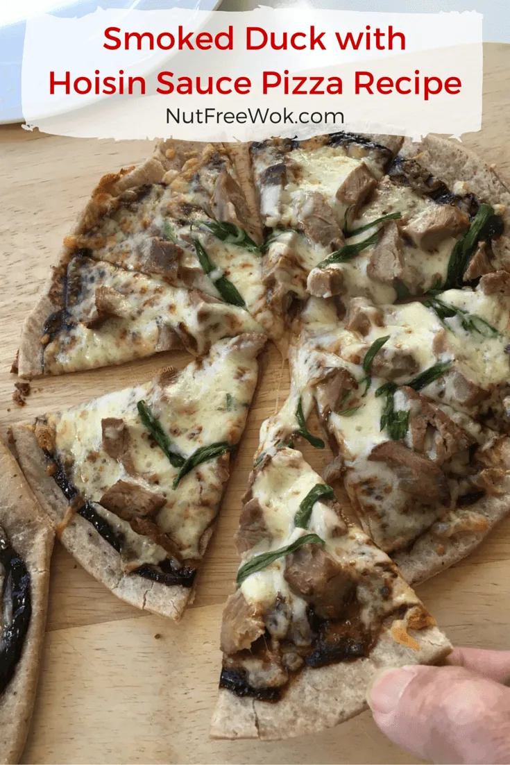 Smoked Duck with Hoisin Sauce Pizza on a wooden cutting board, with two fingers holding one slice