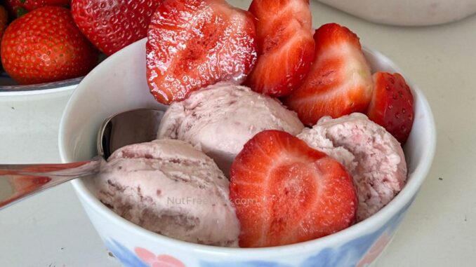 close up of scoops of strawberry ice cream garnished with strawberry slices in a bowl