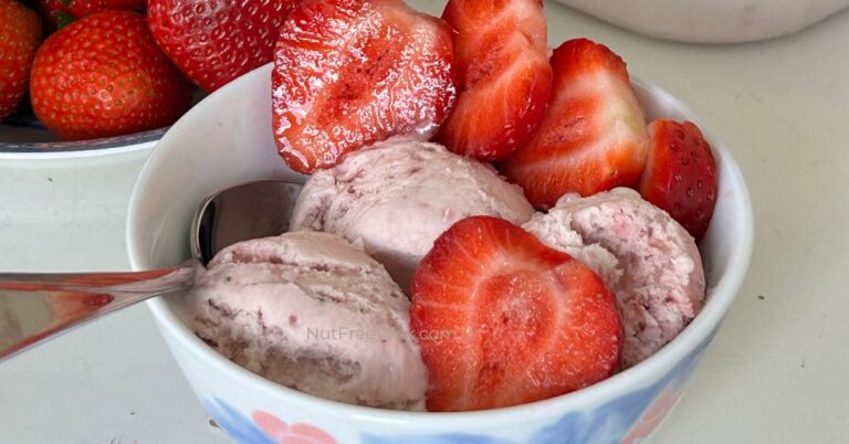 close up of scoops of strawberry ice cream garnished with strawberry slices in a bowl