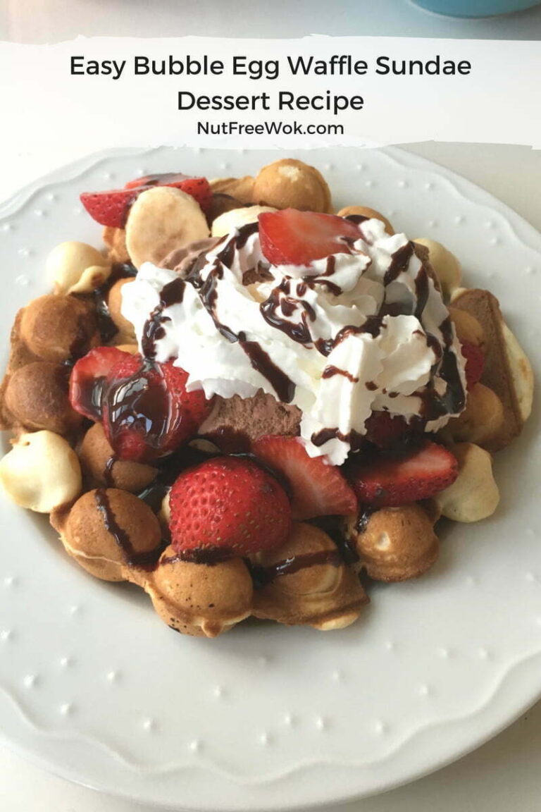 Bubble Egg Waffle Sundae piled high with ice cream, sliced strawberries, whipped cream, and chococlate sauce drizzle. #nutfree #dessert