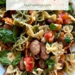 a platter of rainbow bowtie pasta with tomatoes, brie, and sausages