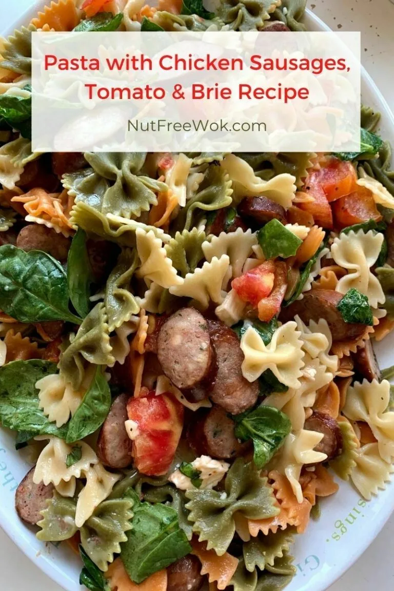 a platter of rainbow bowtie pasta with tomatoes, brie, and sausages