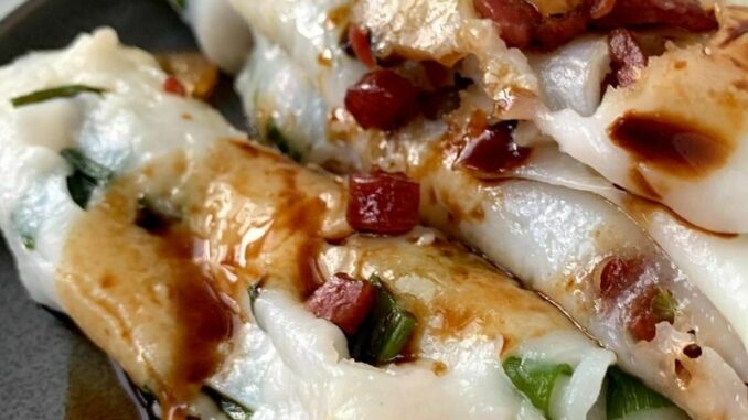 close up of rice noodle rolls with a drizzle of sweet soy sauce on a grey plate
