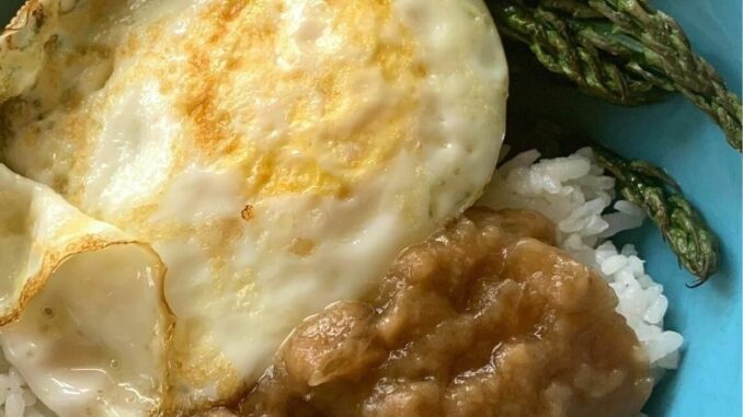 Dairy-free beef gravy over rice, served with an over easy egg and roasted asparagus in a blue bowl