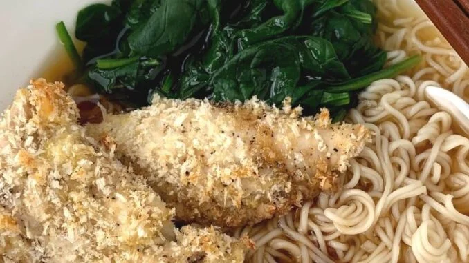 Shoyu ramen with panko breaded chicken and spinach in a white bowl with chopsticks and a soup spoon