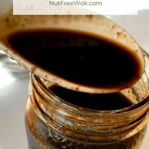 Close up of teriyaki sauce in a spoon with a jar of sauce.