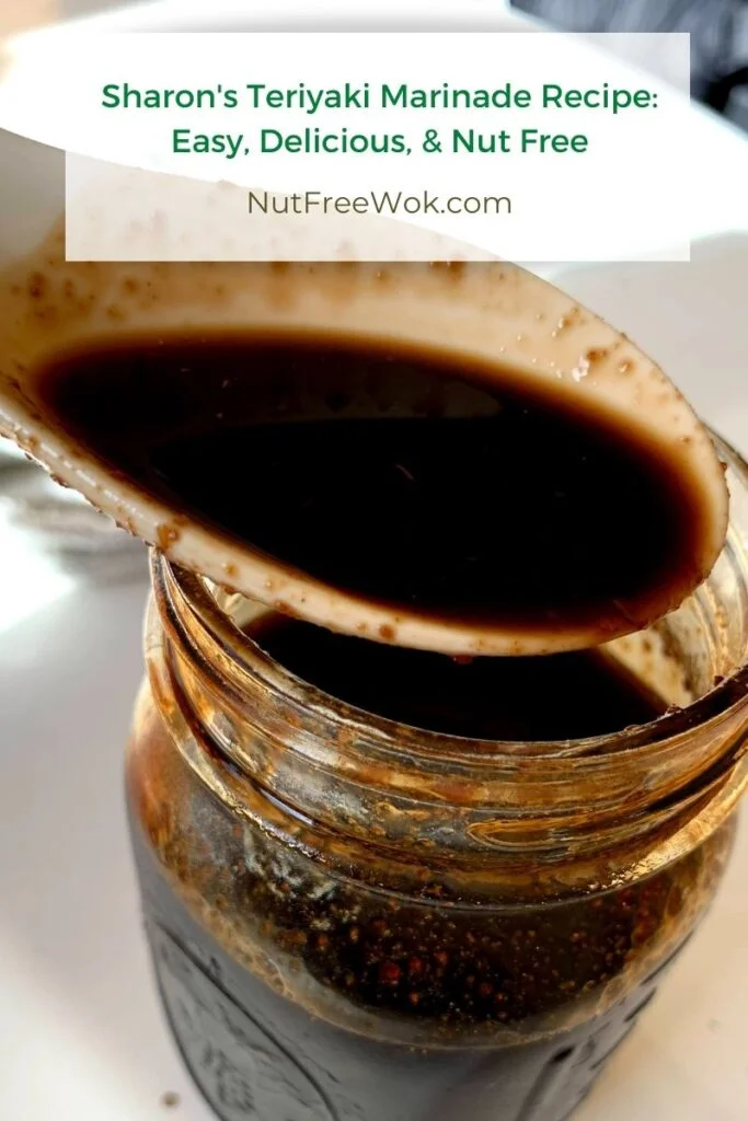 Close up of teriyaki sauce in a white porcelain spoon over a mason jar of sauce. 