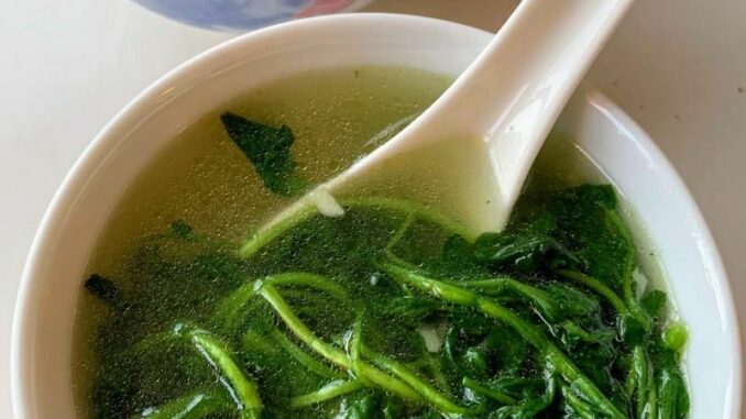 two bowls of watercress and garlic soup in a white soup bowl with white Chinese soup spoons