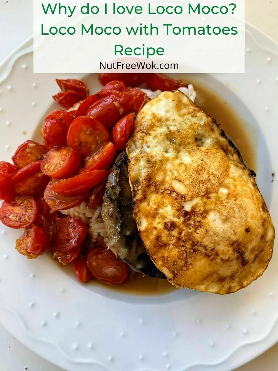 Rice topped with hamburger patty, gravy, egg, and tomatoes on a white plate.