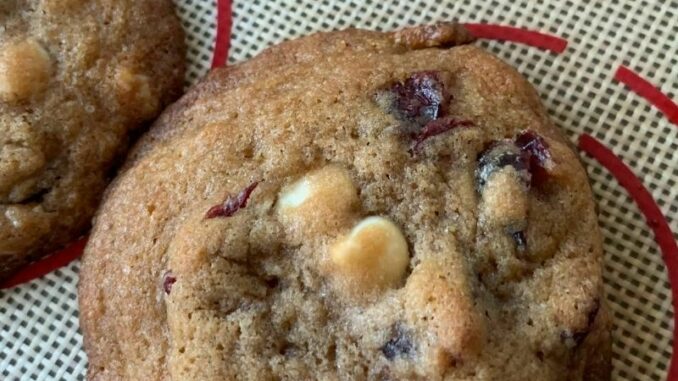 closeup of cranberry and white chocolate chip cookie on a silicone baking sheet