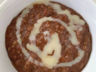 bowl of champorado, chocolate rice porridge, in a bowl with a swirl of sweetened condensed milk