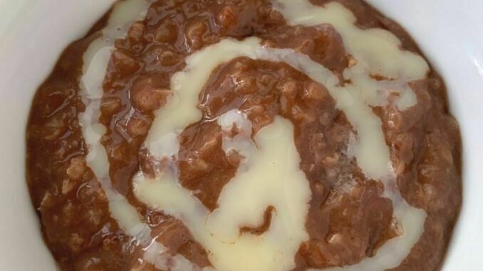 bowl of champorado, chocolate rice porridge, in a bowl with a swirl of sweetened condensed milk