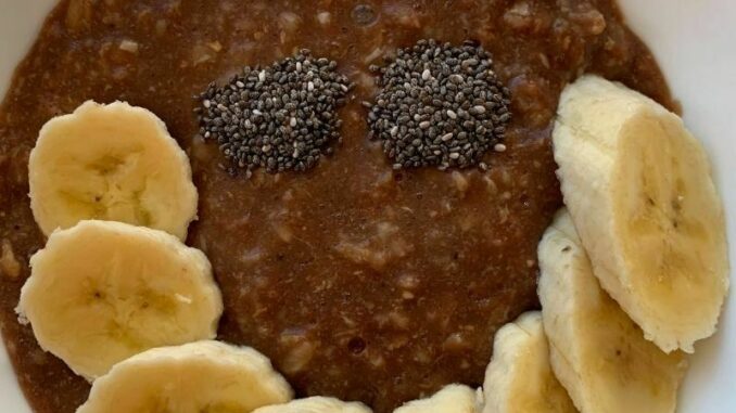 chocolate oatmeal topped with sliced bananas and chia seeds arranged in a smile