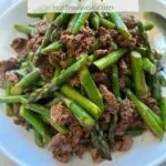 Asparagus stir fried with beef in a white serving plate.