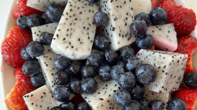 dragon fruit salad with blueberries, strawberries, and watermelon arranged in a white oval serving bowl.