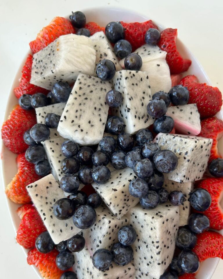 dragon fruit salad with blueberries, strawberries, and watermelon arranged in a white oval serving bowl.