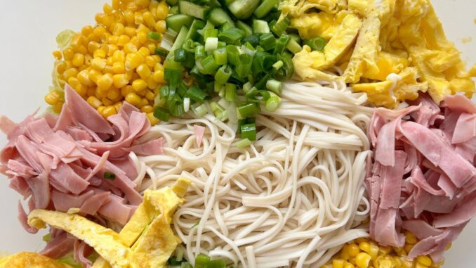 Hiyashi chuka salad with noodles and toppings arranged in a white salad bowl.