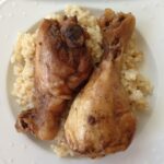 2 chicken drumsticks, plated with brown rice.