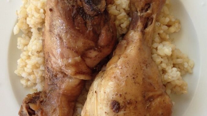 2 chicken drumsticks, plated with brown rice.