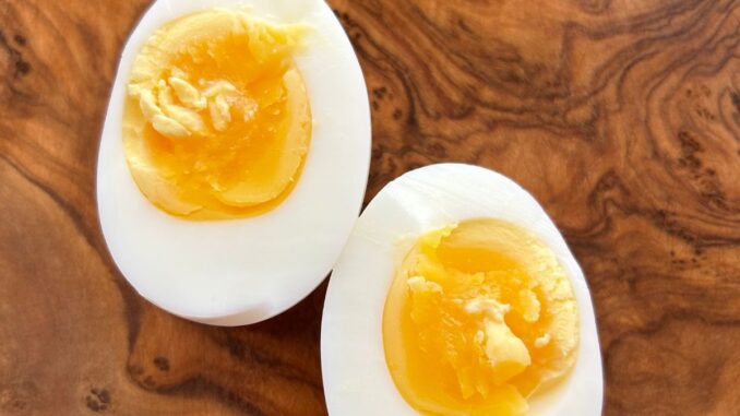 close up of a soft boiled egg cut in half on a wooden cutting board