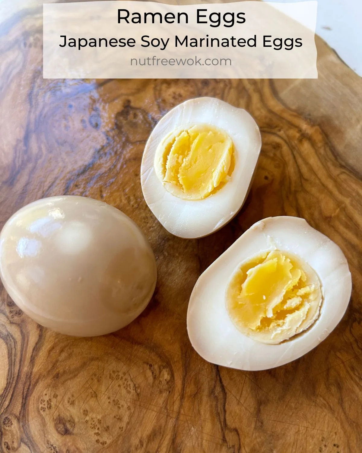 close up of a whole ramen egg and a ramen egg cut in half on a wooden cutting board