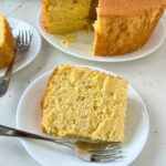 slices of orange chiffon cake on a white cake plate with a fork