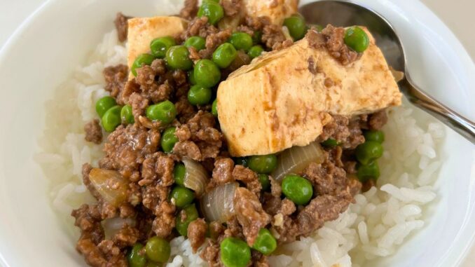 Minced Beef with Tofu, Peas, and Oyster Sauce over rice in a white bowl with a spoon.