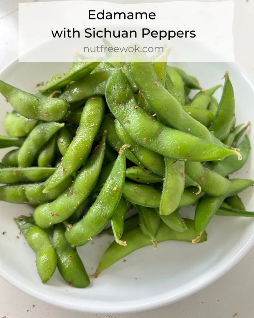 Edamame with Sichuan peppers served in a white bowl.