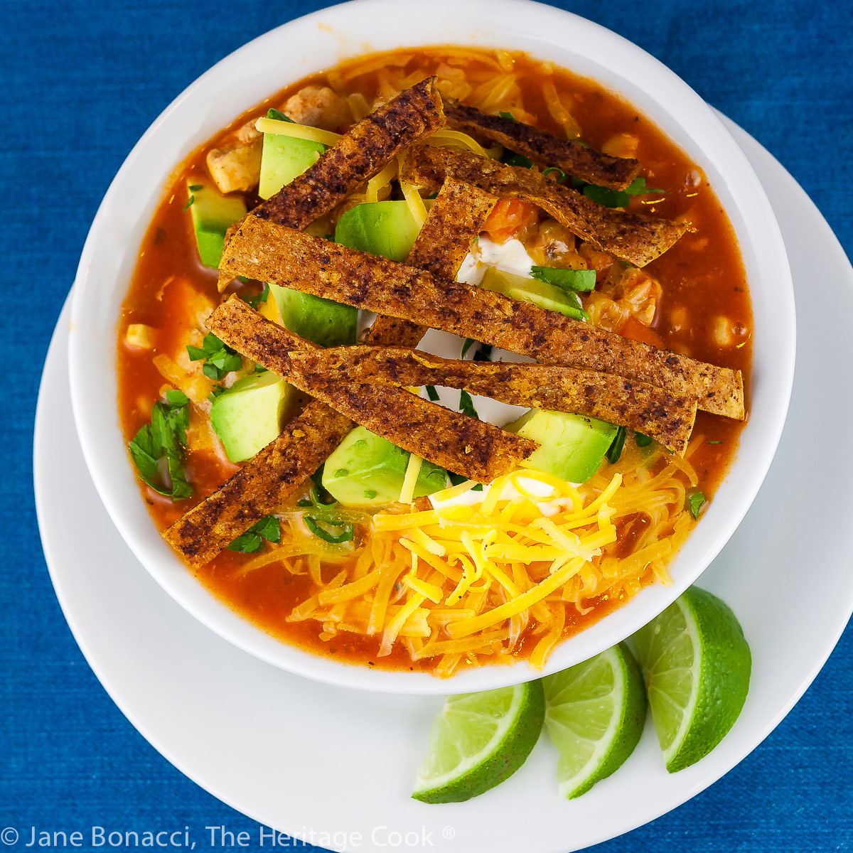 Chile Tortilla Soup in a white bowl with lime wedges on the side