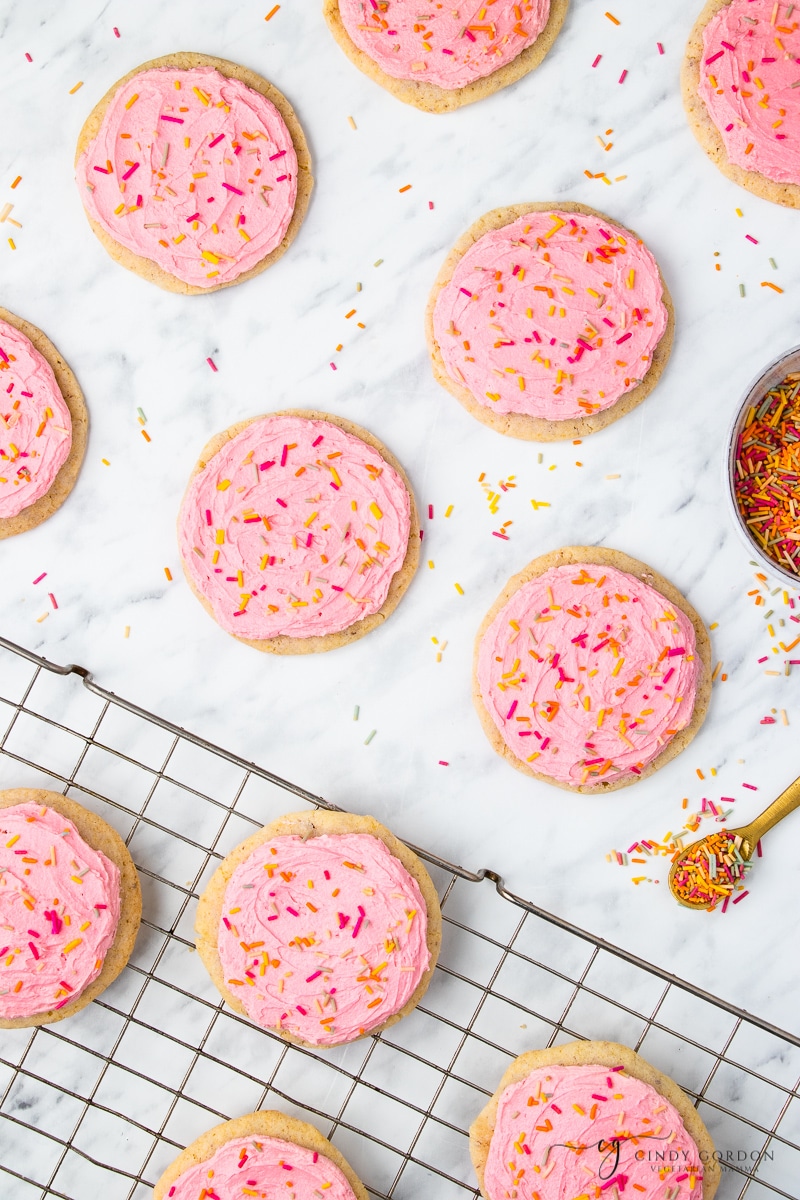 Vegan Frosted Sugar Cookies with pink frosting on a cooling rack or marble surface