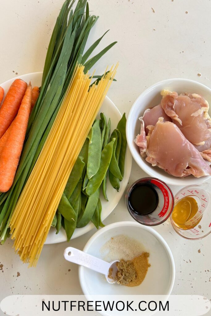 Ingredients used: carrots, garlic chives, thin spaghetti, snow peas are in the white plate. Boneless, skinless chicken thighs are in the white bowl. In the measuring cups, soy sauce and rice vinegar. In the small bowl, sugar, garlic powder, and minced ginger