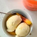 peaches and cream ice cream, served with slices of peaches in a white bowl