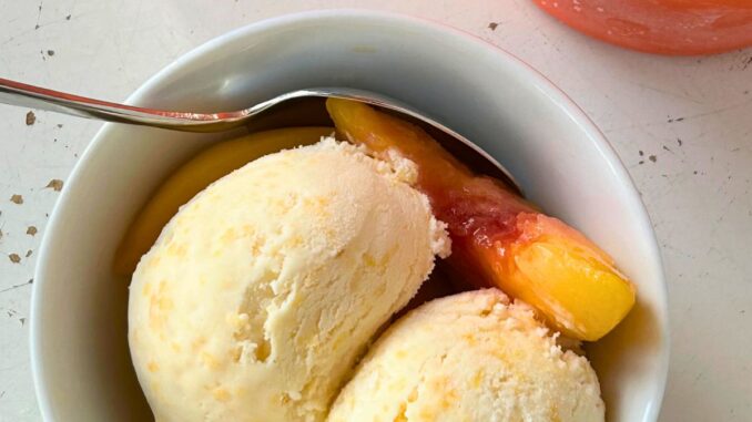 peaches and cream ice cream, served with slices of peaches in a white bowl