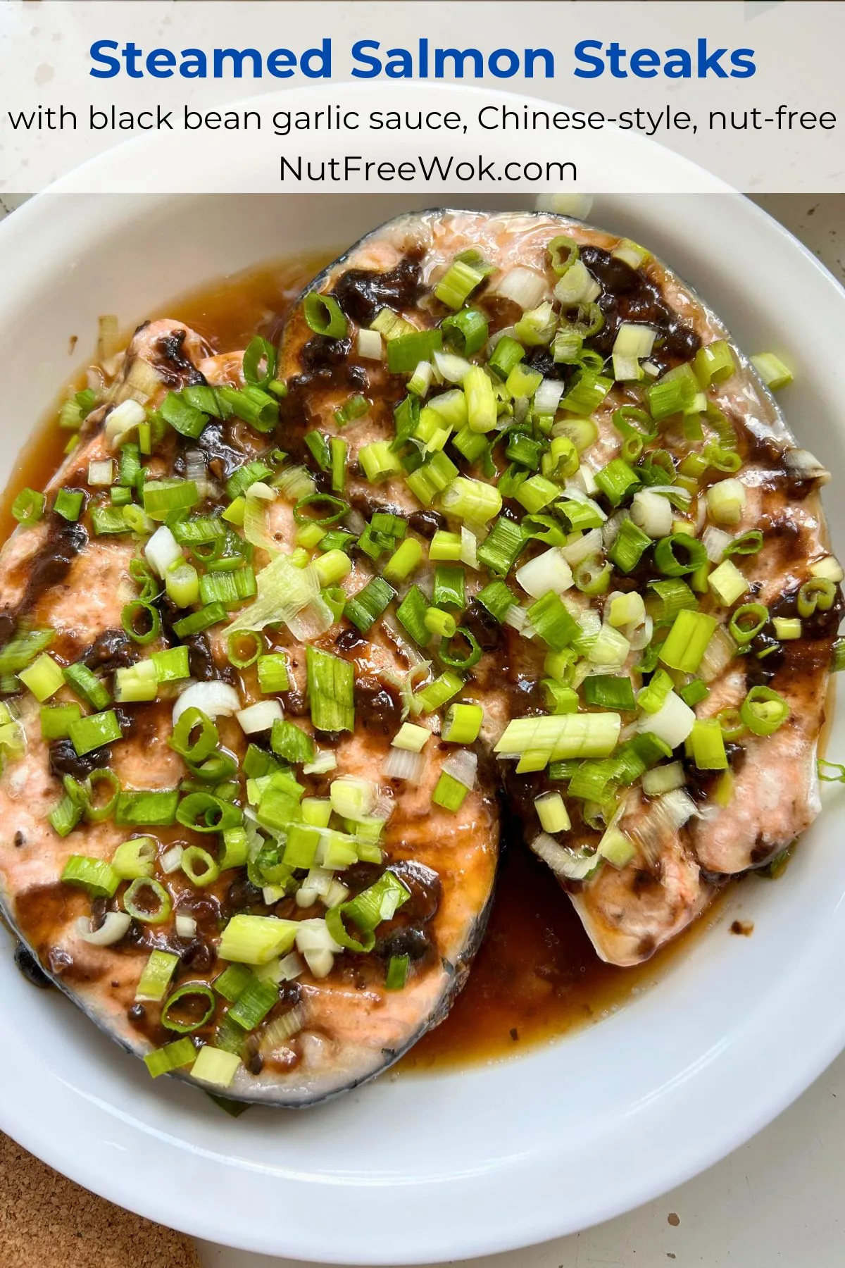 steamed salmon steaks with black bean garlic sauce and topped with scallions in a white serving dish