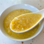 corn and egg drop soup in a porcelain soup spoon and white bowl