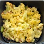 cooked cauliflower with melted cheese in an air fryer basket