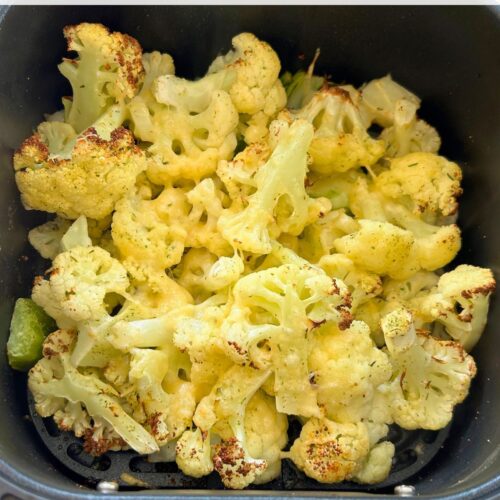 cooked cauliflower with melted cheese in an air fryer basket