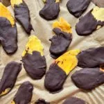 chocolate dipped mango on a parchment paper lined baking sheet