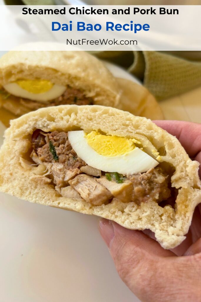 A dai bao cut in half to show the filling ingredients (egg, chicken, sausage, and pork encased with a fluffy steamed bread.