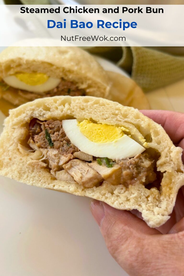 A dai bao cut in half to show the filling ingredients (egg, chicken, sausage, and pork encased with a fluffy steamed bread.